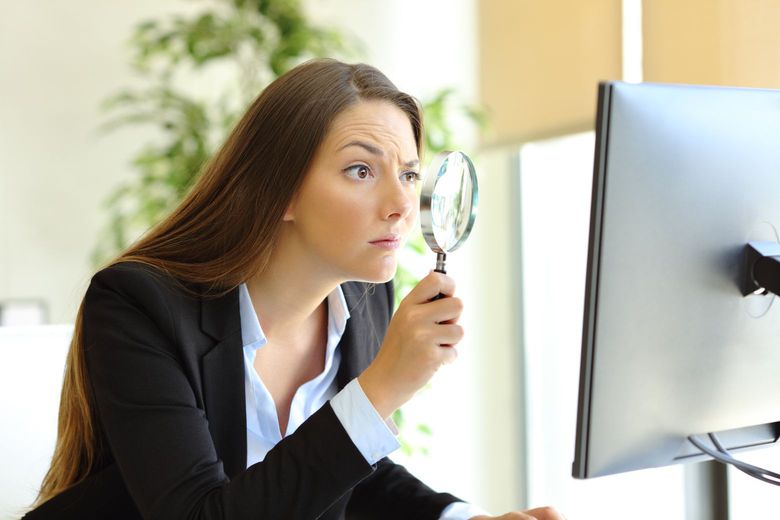 woman looking at her screen with a magnifying glass